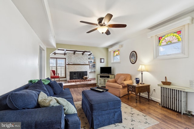 living room with a fireplace, ceiling fan, radiator heating unit, and hardwood / wood-style floors