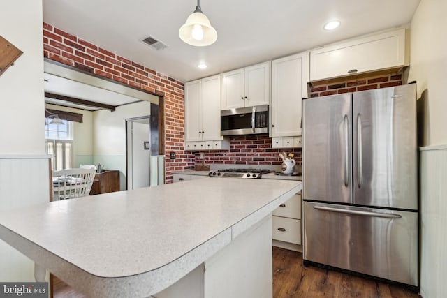 kitchen featuring pendant lighting, white cabinets, dark hardwood / wood-style floors, appliances with stainless steel finishes, and tasteful backsplash