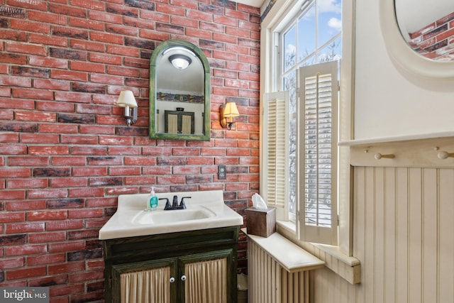 bathroom with vanity and brick wall