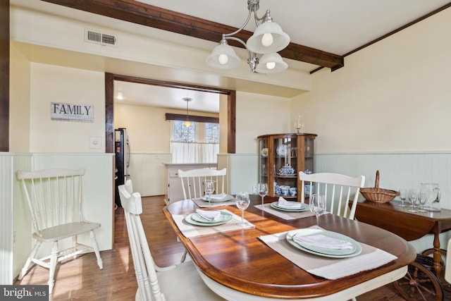 dining area with a chandelier, hardwood / wood-style floors, and beam ceiling