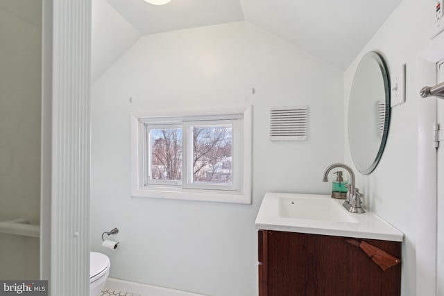 bathroom featuring toilet, vanity, and vaulted ceiling