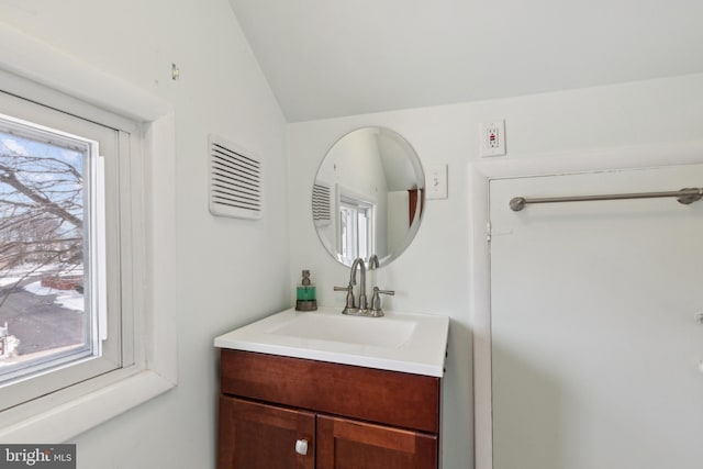 bathroom featuring vanity, a healthy amount of sunlight, and vaulted ceiling