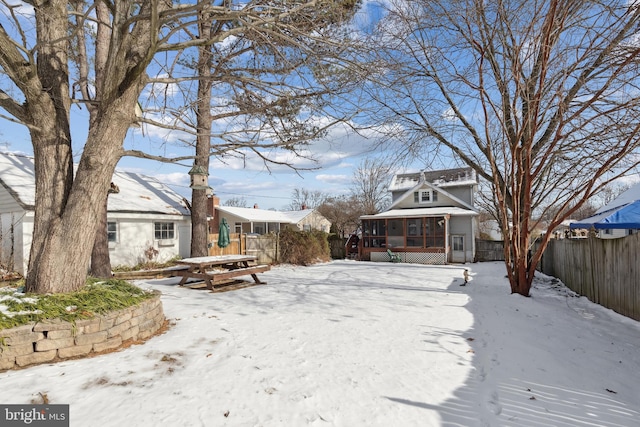 yard layered in snow with a sunroom