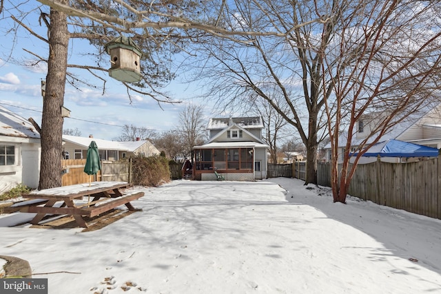 snowy yard featuring a deck and a sunroom