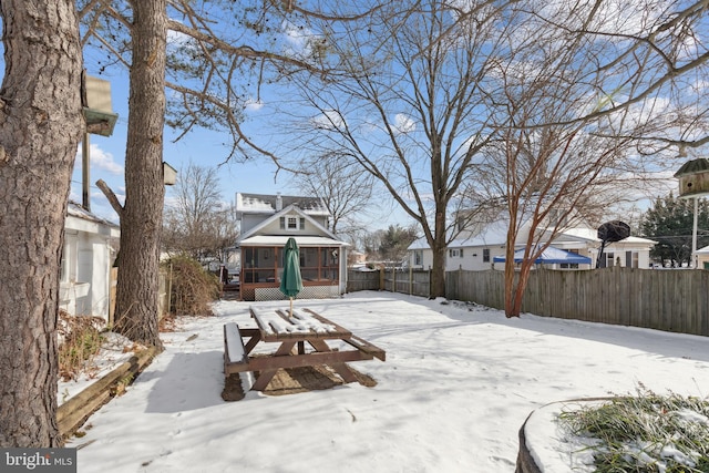 snowy yard featuring a sunroom