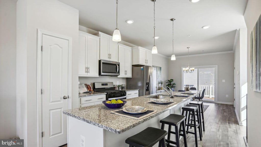 kitchen featuring a breakfast bar area, white cabinetry, a center island with sink, and stainless steel appliances