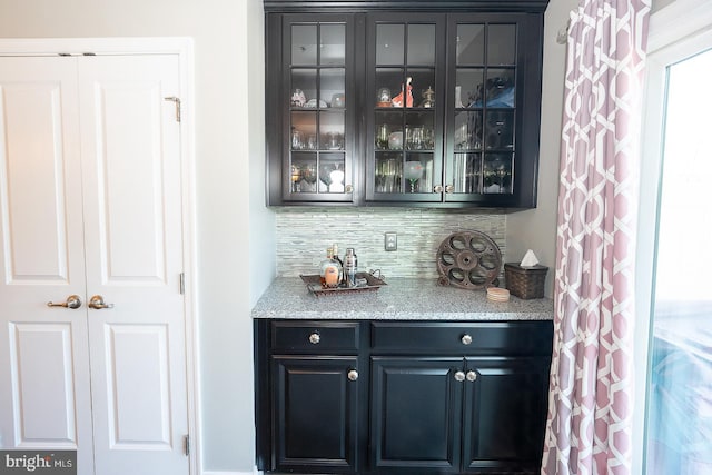 bar with light stone countertops and backsplash