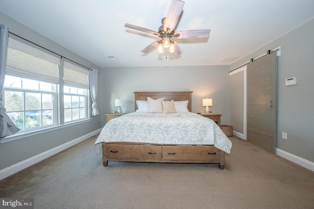 bedroom with ceiling fan, a barn door, and light carpet