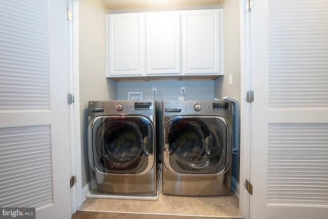 clothes washing area with separate washer and dryer and cabinets