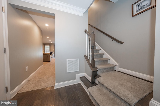 staircase with wood-type flooring and crown molding