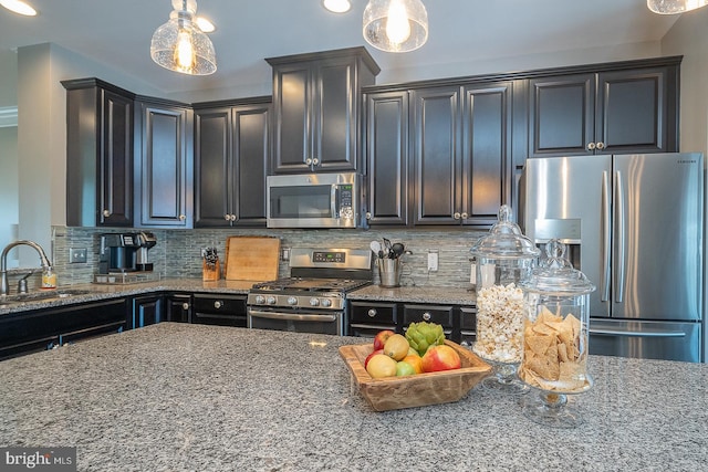 kitchen featuring decorative backsplash, hanging light fixtures, stainless steel appliances, and sink