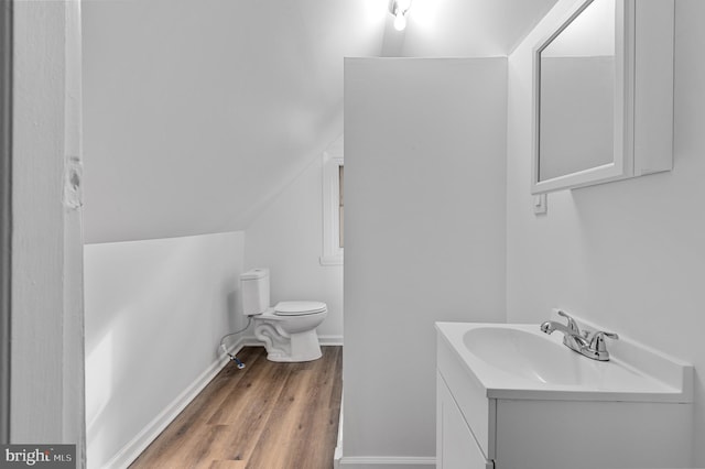 bathroom featuring hardwood / wood-style floors, vanity, toilet, and lofted ceiling