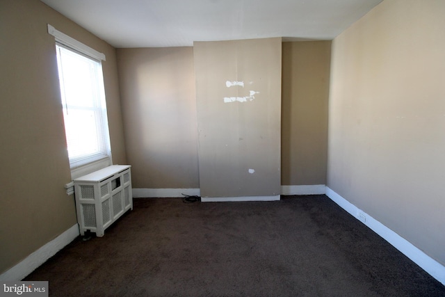 unfurnished room featuring dark colored carpet