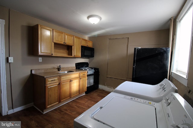 kitchen featuring sink, dark hardwood / wood-style floors, washing machine and dryer, and black appliances