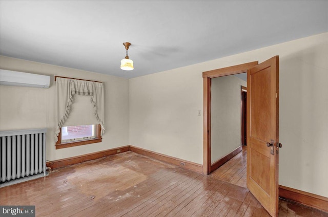 spare room featuring hardwood / wood-style flooring, a wall mounted AC, and radiator heating unit