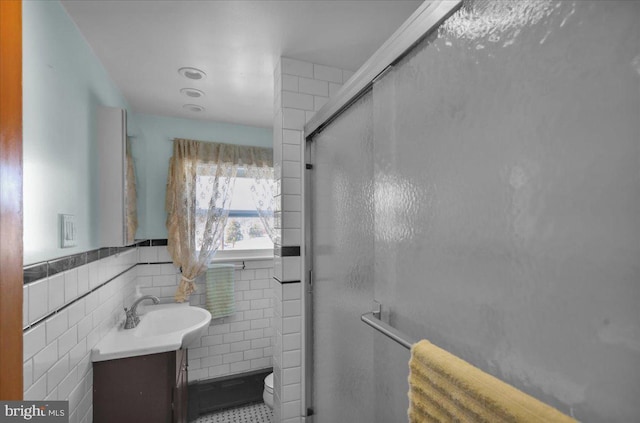 bathroom featuring vanity, toilet, a shower with door, and tile walls