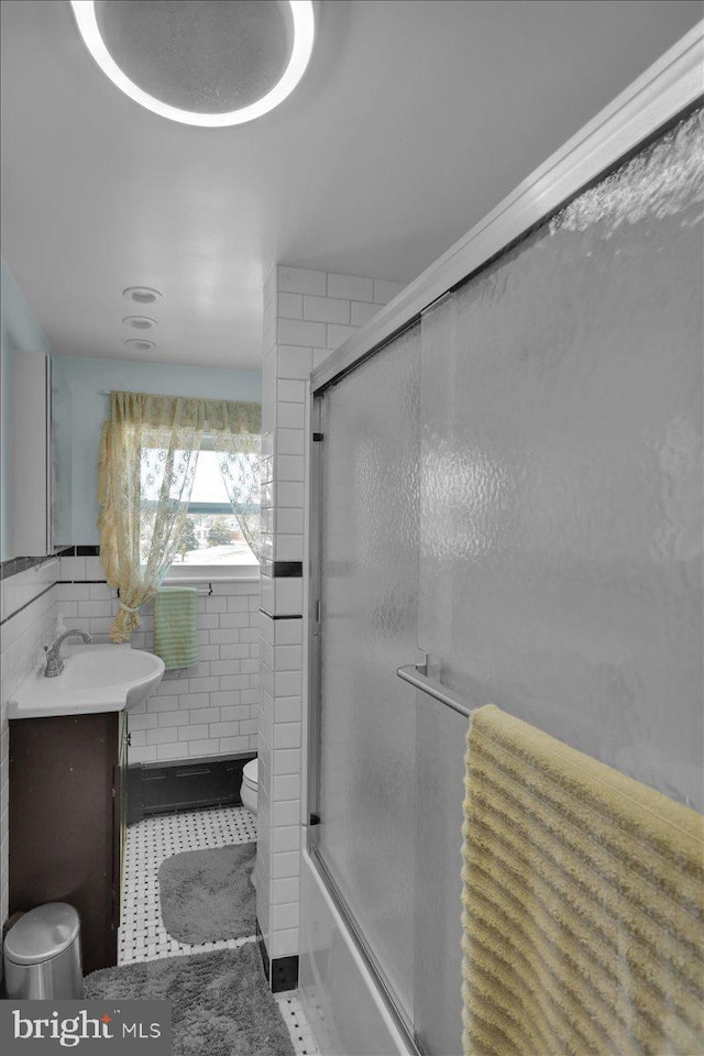 full bathroom with enclosed tub / shower combo, tile patterned flooring, tile walls, vanity, and toilet