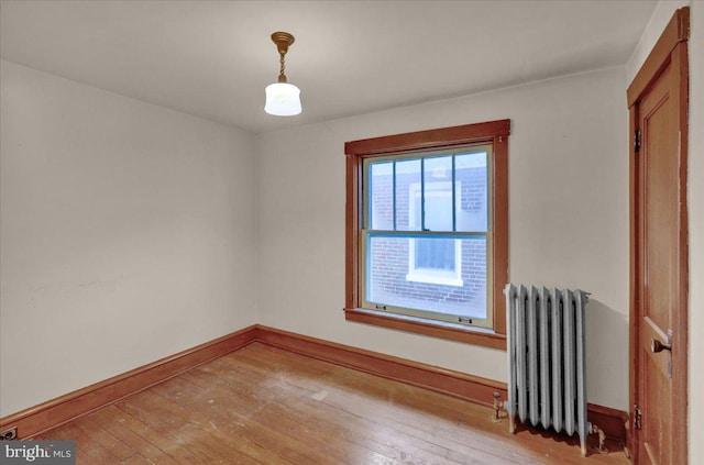 empty room with radiator and hardwood / wood-style floors