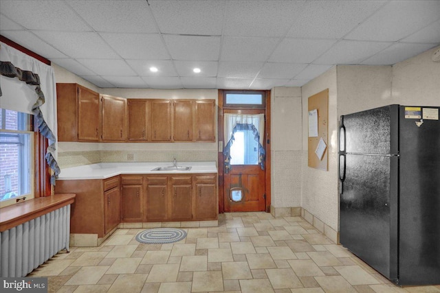 kitchen with black fridge, sink, and a drop ceiling