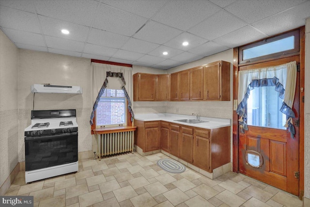 kitchen featuring radiator, sink, gas range gas stove, and a drop ceiling