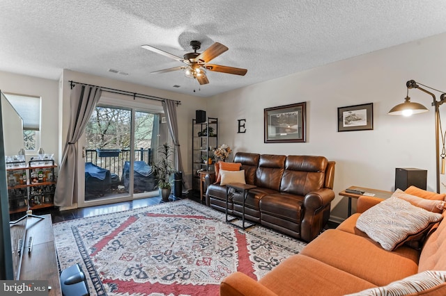 living room featuring ceiling fan, wood-type flooring, and a textured ceiling