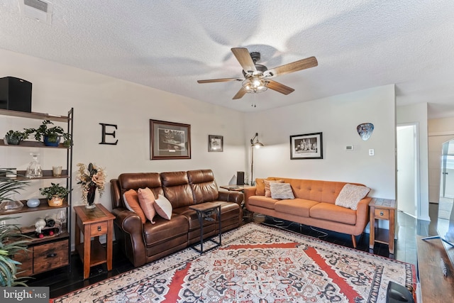 living room with a textured ceiling, hardwood / wood-style flooring, and ceiling fan