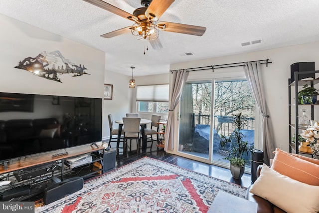 living room with a textured ceiling, dark hardwood / wood-style floors, and ceiling fan