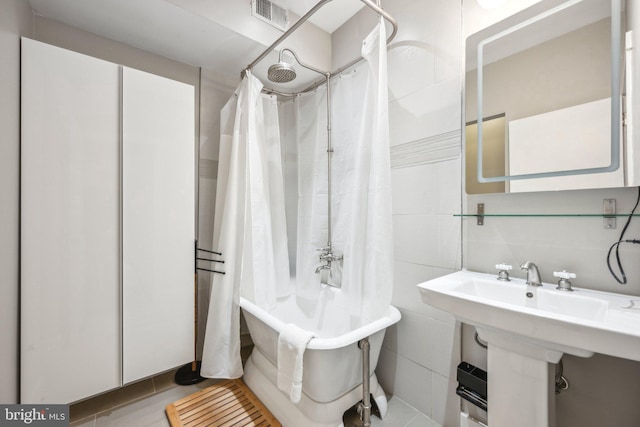 bathroom with tile patterned flooring, shower / tub combo, and tile walls