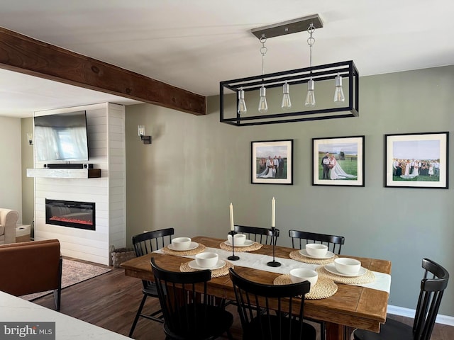 dining room with beam ceiling, dark hardwood / wood-style flooring, and a large fireplace