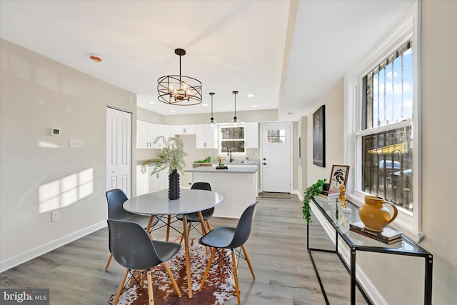 dining space with sink, a notable chandelier, and light hardwood / wood-style flooring