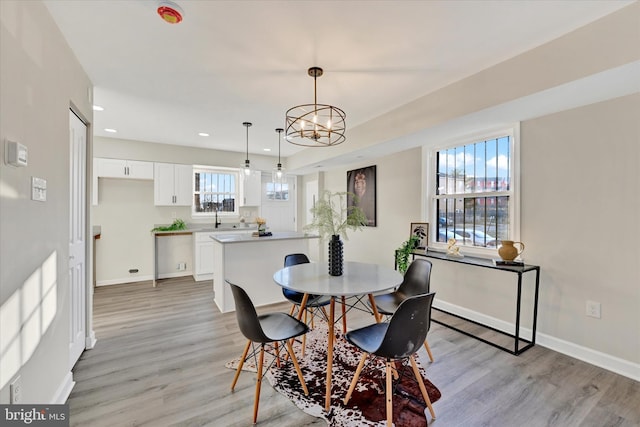 dining space featuring sink, a notable chandelier, and light hardwood / wood-style floors