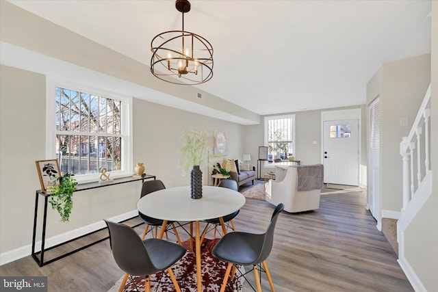 dining area featuring wood-type flooring and a notable chandelier