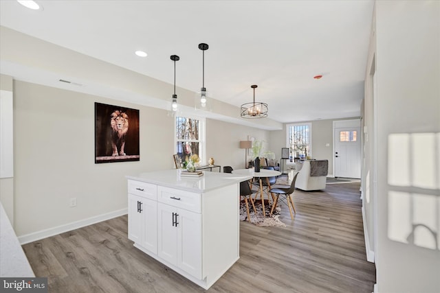 kitchen with white cabinetry, a center island, light hardwood / wood-style floors, and hanging light fixtures