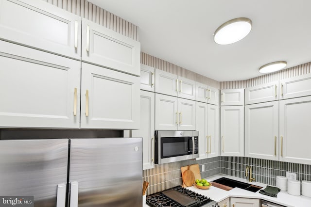 kitchen with white cabinetry, sink, decorative backsplash, and stainless steel appliances