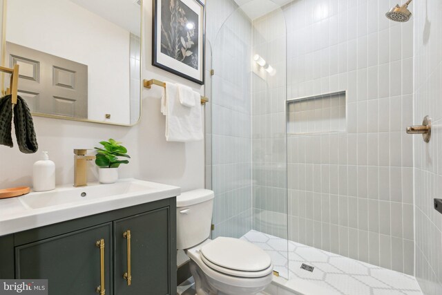 bathroom featuring vanity, tiled shower, and toilet