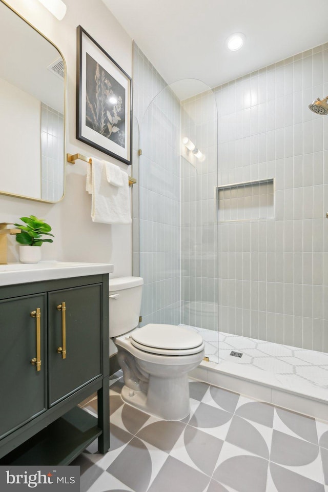 bathroom with vanity, toilet, and a tile shower