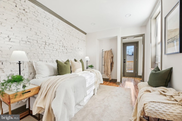 bedroom featuring light hardwood / wood-style floors and brick wall