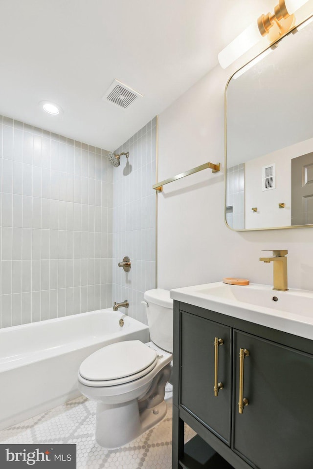 full bathroom with tile patterned flooring, tiled shower / bath, vanity, and toilet