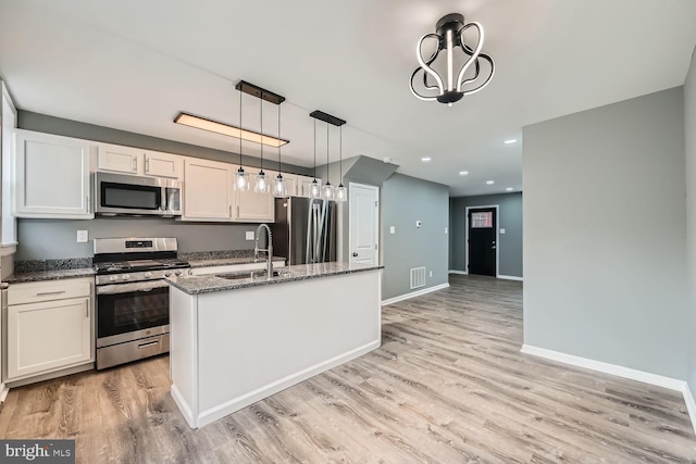 kitchen featuring a kitchen island with sink, sink, decorative light fixtures, white cabinetry, and stainless steel appliances