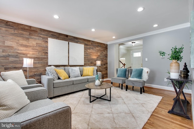 living room with light wood-type flooring, crown molding, and wood walls