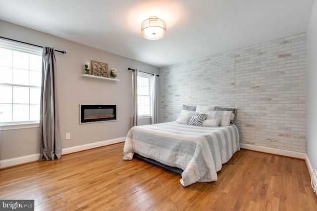 bedroom featuring brick wall and light wood-type flooring