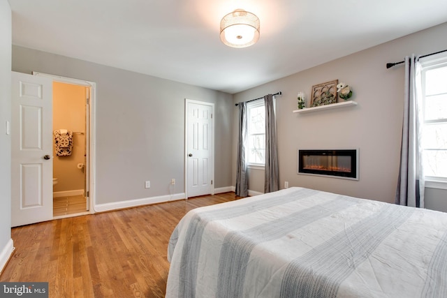 bedroom with light hardwood / wood-style floors and connected bathroom