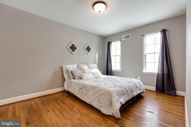 bedroom with wood-type flooring and multiple windows