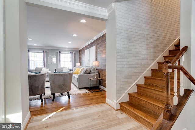 stairs with wood-type flooring, ornamental molding, and brick wall