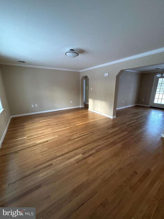 unfurnished living room featuring ornamental molding and dark wood-type flooring