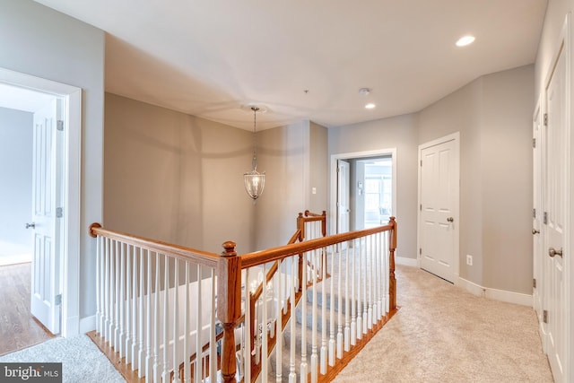 corridor featuring light carpet and a notable chandelier