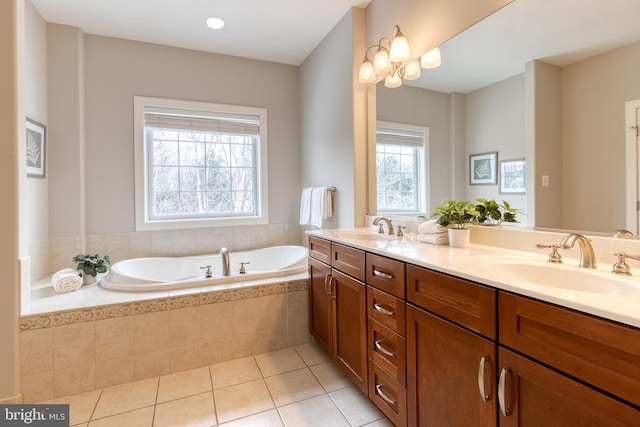 bathroom with tiled bath, a wealth of natural light, vanity, and tile patterned flooring