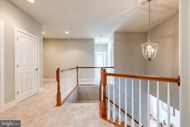 hall featuring light colored carpet and an inviting chandelier