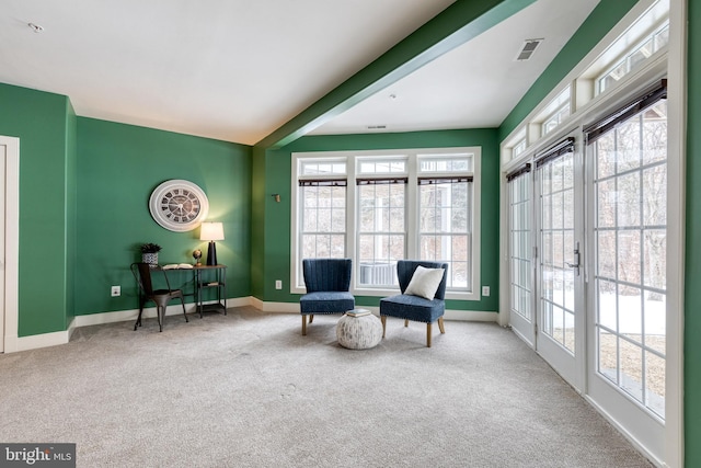 sitting room featuring plenty of natural light, light colored carpet, beamed ceiling, and french doors