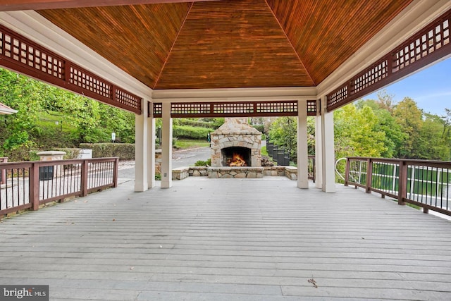 wooden terrace featuring a gazebo and an outdoor stone fireplace